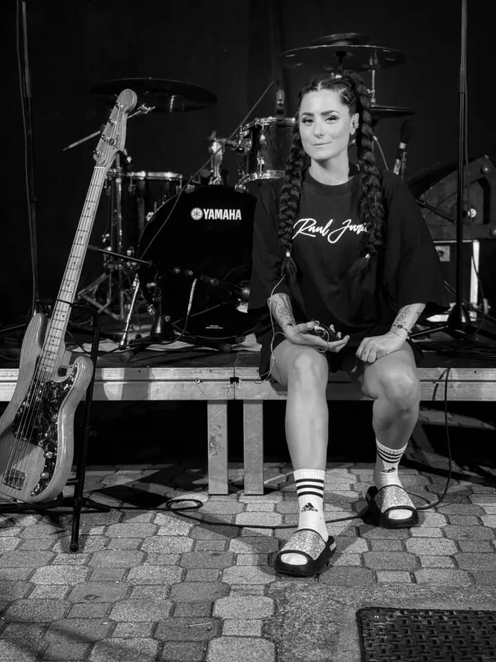 Laura Santos sentada en el escenario junto a la batería y el bajo
